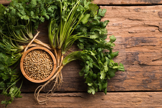 Coriander seeds and leaves on a wood background