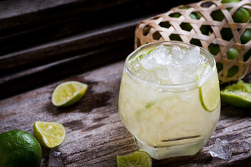 Cocktail with ice and lime slice on old wood table