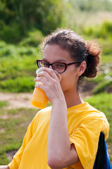 Fototapeta premium Girl in a yellow T-shirt is drinking orange juice
