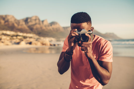 Black guy using digital camera on beach