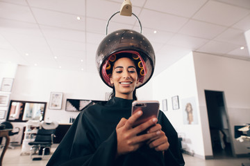 Woman using mobile phone at the beauty spa - obrazy, fototapety, plakaty