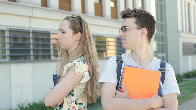 Pair of students standing back to each other and look offended, steadycam shot
