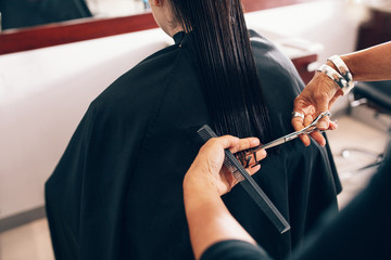 Hairdresser trimming a woman's hair at salon