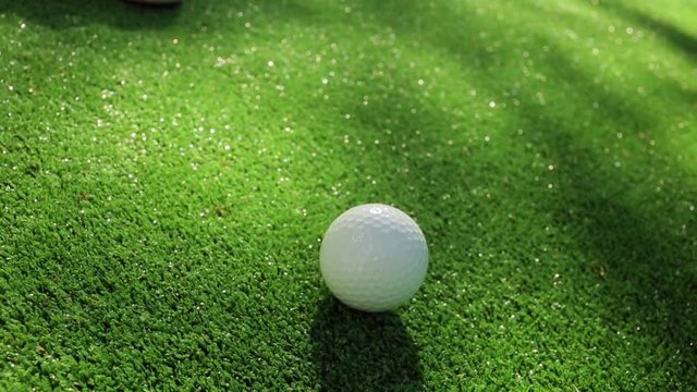 Close-up of golfer using putter to sink short putt into hole