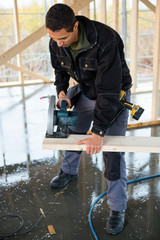 Carpenter Cutting Wood With Electric Saw At Site