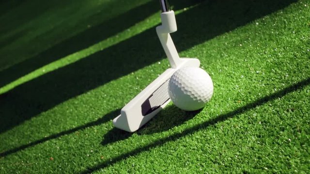 Close-up of golfer using putter to sink short putt into hole