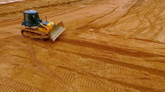 Sand mining industry. Bulldozer machine. Crawler bulldozer moving at sand mine. Mining machinery working at sand quarry. Drone view of mining equipment at industrial sand quarry. Earth mover