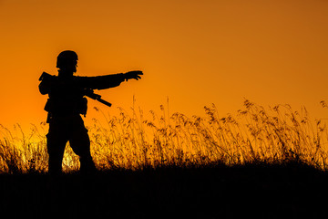 Fototapeta na wymiar military soldier with weapons at sunset. shot, holding gun, colorful sky. military concept.