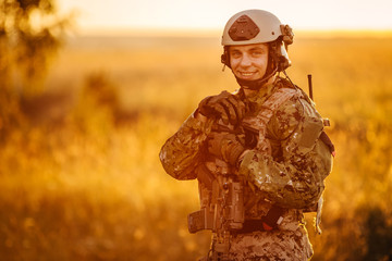 portrait of young soldier face with camouflage against a sunset background