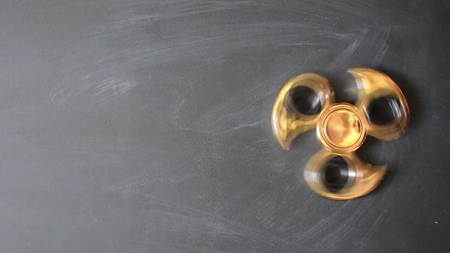 fidget spinner rotate on a black board from above, engine rotate top view with copy space