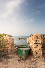 Old boat among stone walls on the coast of the island of Formentera. Spain