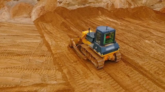 Bulldozer machine moving sand in sand quarry. Mining equipment at quarry. Crawler bulldozer moving sand. Earth moving machine. Aerial view of crawler bulldozer mining sand. Mining machinery