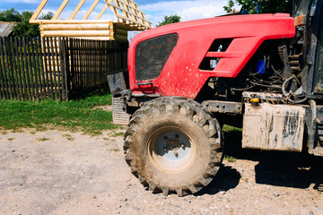 Obraz premium Red tractor on the road. Big dirty off-road tires.