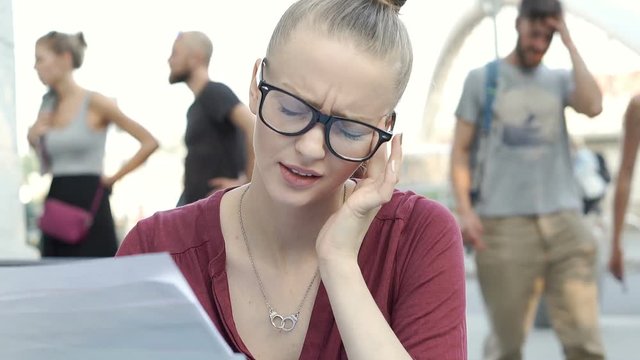 Beautiful woman having headache while working on documents in the outdoor cafe, steadycam shot
