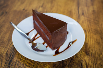 Piece of chocolate cake with spoon on white plate