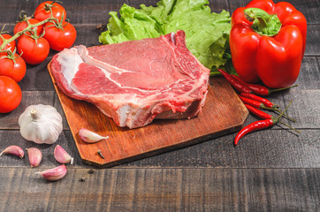 A raw piece of beef with peppers, tomatoes, herbs and garlic