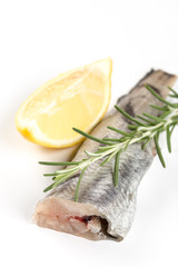 Fresh raw hake fish on the white background with rosemary and lemon