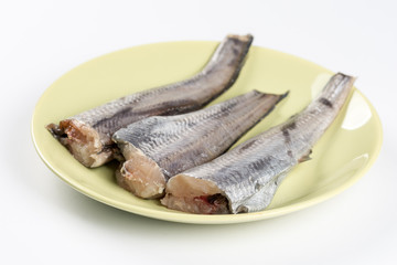 Fresh raw hake fish on the green plate above white background