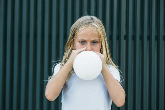 Girl blowing balloon outside
