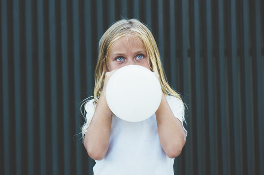 Girl blowing balloon outside