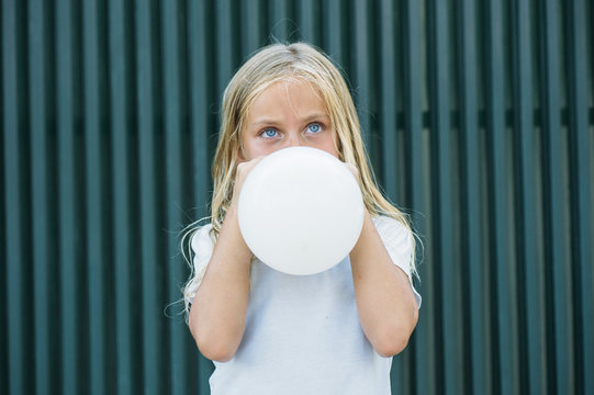 Girl blowing balloon outside