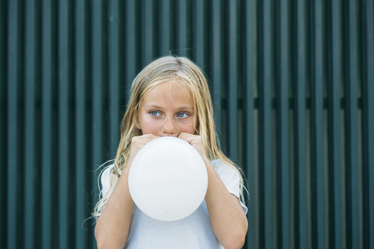Girl blowing balloon outside