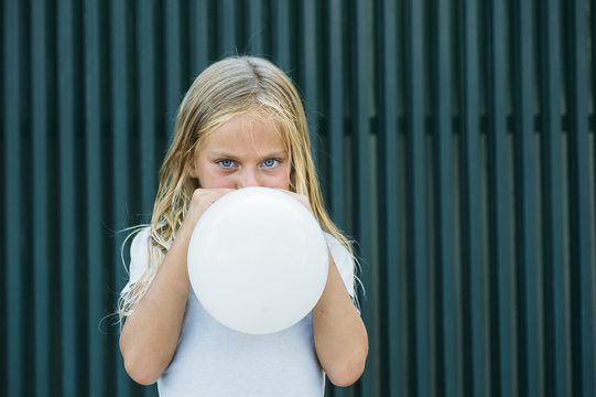 Girl blowing balloon outside