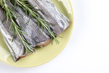 Flat lay above plate with raw hake fish and rosemary branches