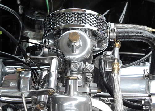 details of a shiny polished chome and steel vintage sports car engine