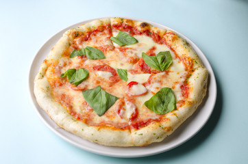 Pizza margarita on a white plate and blue background