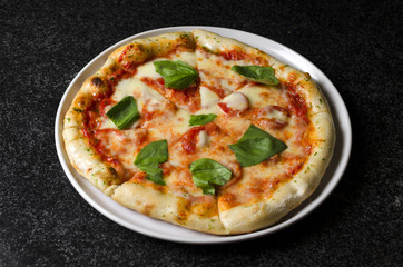 Pizza margarita on a white plate and blue background