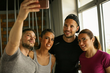 Group of smiling people making self-picture in gym. People workout in gym.