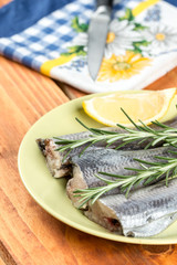 Selective focus on hake fish on the plate with rosemary and lemon