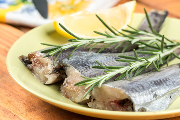 Fresh raw hake fish on the plate with rosemary and lemon