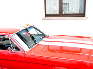 Roter amerikanischer Sportwagen und Pony Car der Sechziger Jahre mit weißen Streifen auf der...