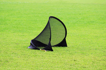 Small football gate for training kids to sports football in a stadium with green lawn grass