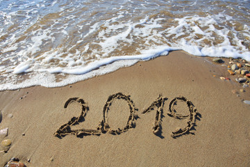New year 2019 written in sand.