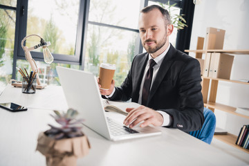 handsome young businessman using laptop with cup of coffee