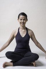 Fototapeta premium Portrait of mid Asian woman is playing yoga in studio in black sport wear.