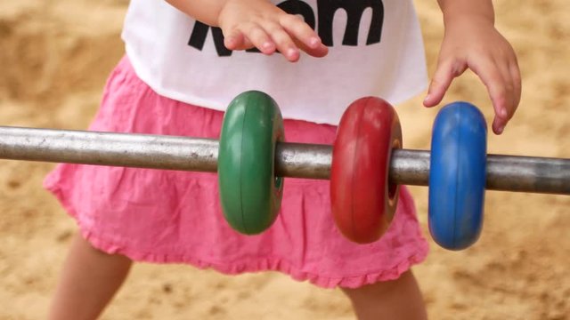 Little girl moves colored wooden rings.