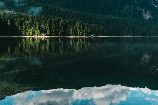 Reflection of a forest and boat house at lake Eibsee during morning