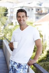 Fototapeta premium Man enjoying morning coffee on balcony, portrait