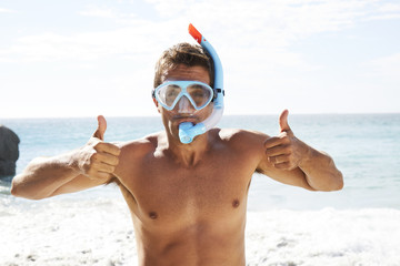Guy in beach in scuba mask and snorkel with thumbs up
