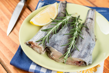 Plate full with raw hake fish and lemon and rosemary branch