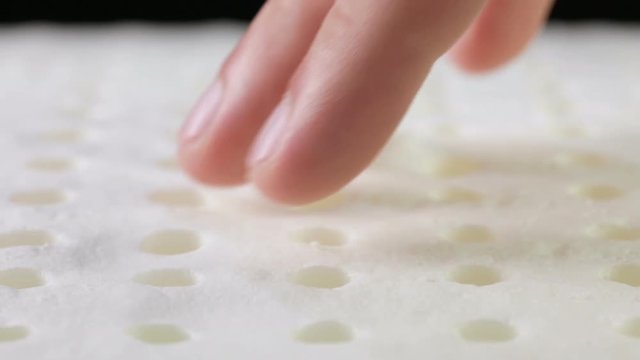 Mani di un uomo che stanno toccando un materasso in memory foam per testare la sua efficacia.