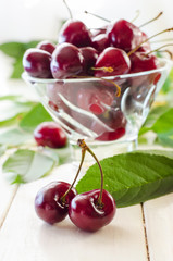 Ripe maroon cherries in a glass vase and a jar