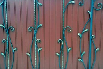 фрагмент  красных железных  дверей с кованными прутьями и красивым узором