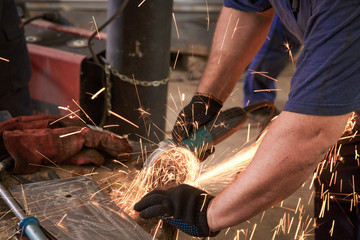 Close-up of worker cutting metal with grinder. Sparks while grinding iron.