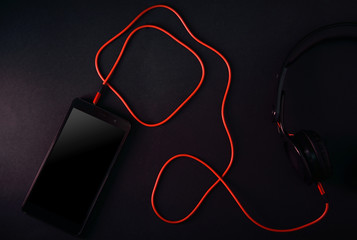 Headphones for music with a phone on a dark background in dark colors