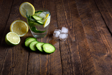 Water with lemon,lime  mint and cucumber on the wooden dark background. Water Detox.on wooden background